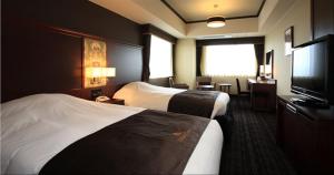 a hotel room with two beds and a flat screen tv at Hotel Monterey Grasmere Osaka in Osaka