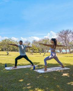a man and a woman doing yoga in a park at Melia Bali in Nusa Dua