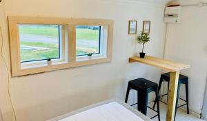 Zimmer mit einem Bett, einem Fenster und zwei Hockern in der Unterkunft Dancamps Holmsland in Hvide Sande