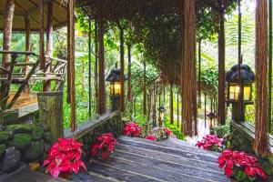 une passerelle en bois dans une forêt avec des lumières et des fleurs dans l'établissement Fig Tree Hills Resort (花果山度假村), à Bayan Lepas