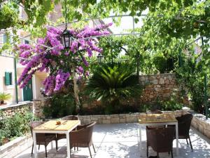 a patio with tables and chairs and purple flowers at Apartments Paloc in Bol