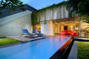 - une piscine avec 2 chaises et une maison dans l'établissement Bali Island Villas & Spa CHSE Certified, à Seminyak