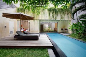 a swimming pool with two couches and an umbrella at Bali Island Villas & Spa CHSE Certified in Seminyak