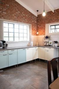 uma cozinha com armários brancos e uma parede de tijolos em East of East Guest Cottage em Avondzon