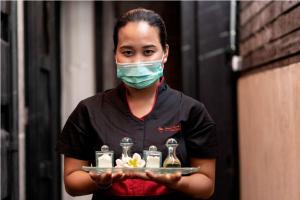 a woman wearing a face mask holding a tray of food at Bali Island Villas and Spa Seminyak in Seminyak