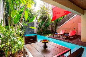 a patio with a table and chairs and a pool at Bali Island Villas and Spa Seminyak in Seminyak