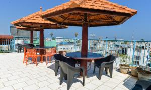 a patio with tables and chairs under an umbrella at Hotel Corbelli in Puducherry