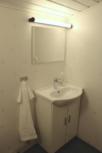 La salle de bains blanche est pourvue d'un lavabo et d'un miroir. dans l'établissement Kärraton Stugor, à Åhus