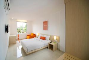 a white bedroom with a bed and a window at Zuri Express Hotel Pekanbaru in Pekanbaru