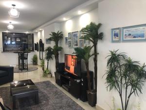 uma sala de estar com palmeiras e uma televisão em Santorini Seafront Stay em Alexandria