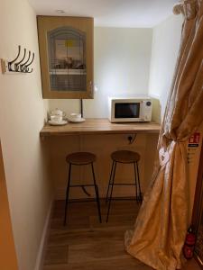 a kitchen with a counter with a microwave and two stools at Deer Lodge in Thornton Curtis