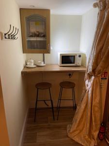 a kitchen with a counter with a microwave and two stools at Deer Lodge in Thornton Curtis +4 photos