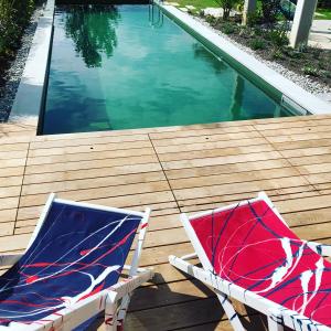 Duas cadeiras sentadas num deque de madeira junto a uma piscina em SeeSucht-Apartment No86 mit Terrassen, Sauna & Pool em Bodman-Ludwigshafen