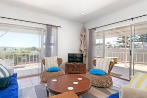 Una sala de estar con una mesa y sillas y un televisor. en Kite Villa Langebaan, en Langebaan