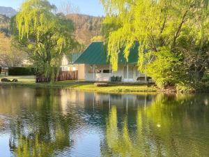 una casa con techo verde junto a un lago en Mkomazana Mountain Cottages, en Himeville