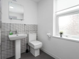 a bathroom with a toilet and a sink and a window at Apex Living NE - Beachville House II 4 Beds FREE PARKING in Sunderland