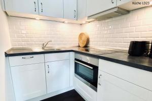 una cocina blanca con armarios blancos y fregadero en Haus Lieke Deeler en Norderney