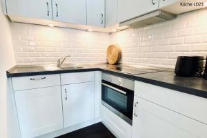 a white kitchen with white cabinets and a sink at Haus Lieke Deeler in Norderney