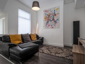 a living room with a black leather couch and a painting at Apex Living NE - Beachville House II 4 Beds FREE PARKING in Sunderland