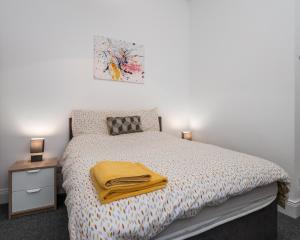 Apex Living NE - Beachville House II 4 Beds FREE PARKING في سندرلاند: غرفة نوم عليها سرير مع بطانية صفراء