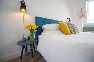 a bedroom with a bed with a blue headboard and a table with yellow flowers at The Coffee Loft in Padstow +7 photos
