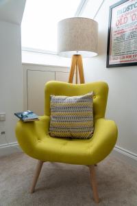 a yellow chair with a pillow and a lamp at The Coffee Loft in Padstow