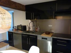 una cucina con armadi neri e lavandino di La petite maison CARRÉ a Talant Altre 2 foto