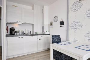 a kitchen with white cabinets and a table with a chair at BRN Seemoewe in Laboe