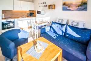 a living room with a blue couch and a table at Lüttje Nest in Dornumersiel