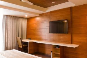 a room with a desk and a tv on a wall at Ananth The Grand in Hubli