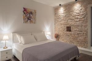 1 dormitorio con cama y pared de piedra en Casa di Pietra, en Šibenik