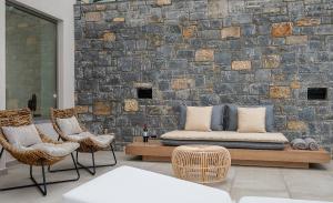 a patio with a bed and chairs and a brick wall at Ligaria Mare in Agia Pelagia