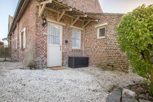 ein Backsteinhaus mit einer weißen Tür und einem Fenster in der Unterkunft Maison Alice /Maison avec vue sur les champs in Comines