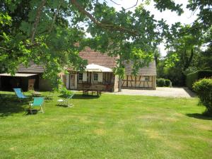 ein Haus mit einem Garten mit Stühlen und einem Tisch in der Unterkunft La Ferme de Montboulan in Salbris