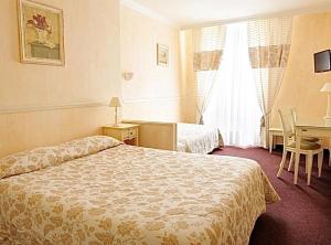 ein Hotelzimmer mit 2 Betten und einem Schreibtisch in der Unterkunft Le Grand Hôtel in Souillac