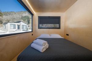 a bedroom with two beds and a large window at ROOMBOX Likani in Borjomi