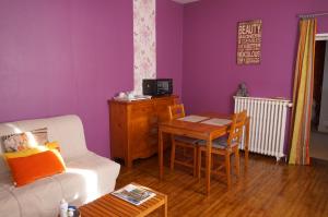 uma sala de estar com paredes roxas, uma mesa e um sofá branco em Chambre d'Hôtes - l'Ephémère em Limoges