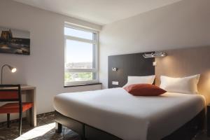 a bedroom with a large white bed and a window at The Originals Boutique, Hôtel d'Alsace, Strasbourg Sud in Illkirch-Graffenstaden +35 photos