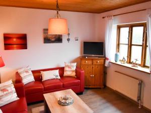 a living room with a red couch and a tv at Ferienhaus Deerberg in Hasselberg