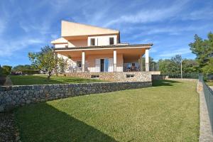 a house with a stone wall and a grass yard at Villa Cactus in Inca
