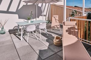 eine Terrasse mit Tisch und Stühlen und einem Sonnenschirm in der Unterkunft ALDARA SUITES in Santiago de Compostela