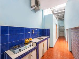 uma cozinha em azulejos azuis com um fogão e um lavatório em SPOT ON 90744 Alika Homestay em Demak