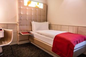 a small room with a bed with a red blanket at Hotel St.Gotthard in Zurich
