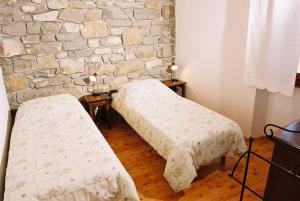 two beds in a room with a stone wall at Bordon wines, estate with accommodation in Dekani