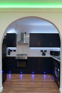 een keuken met zwarte kasten en een fornuis met oven bij Kitchener house in Leeds