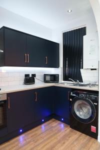 cocina con armarios negros y lavadora en Kitchener house en Leeds