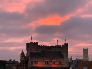 un castillo con dos banderas encima al atardecer en Great en Gante