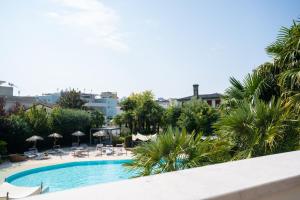 uma vista para uma piscina com cadeiras e guarda-sóis em Villa Carlotta Jesolo Lido em Lido di Jesolo