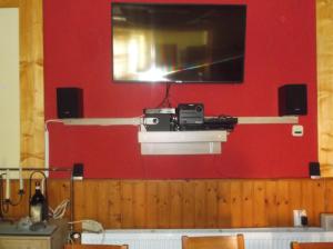 a tv on a wall with a red wall at Vali Vendégház in Gyula