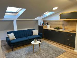 a living room with a blue couch and a kitchen at Pristina Select Apartments in Prishtinë